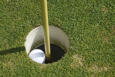 Golf Ball in Hole Next to Base of Pin